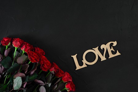Red roses flowers with wooden word LOVE on black background withの写真素材