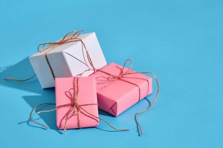 Craft paper wrapped present boxes craft rope bow ribbon with shadow on blue background, top view....