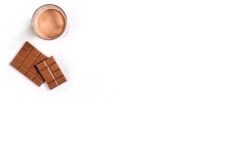 Glass of chocolate milk with chocolate bar on white background with space for text or design. Still...