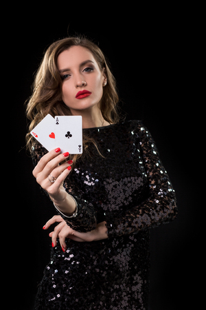 Young woman holding playing cards against a black backgroundの写真素材