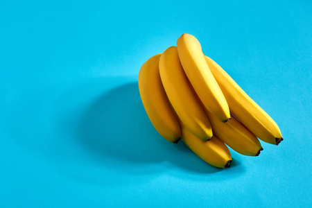 Yellow ripe bananas on blue background with space for text or design. Top viewの写真素材
