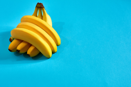 Fresh bananas close up on bright blue background. Flat lay. Summer concept.の写真素材