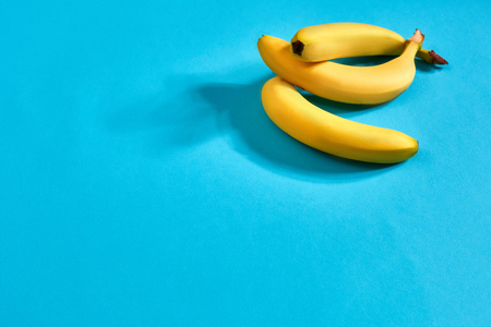 Fresh bananas close up on bright blue background. Flat lay. Summer concept. Still life. Copy spaceの写真素材