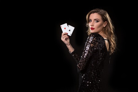 Young woman holding playing cards against a black backgroundの写真素材