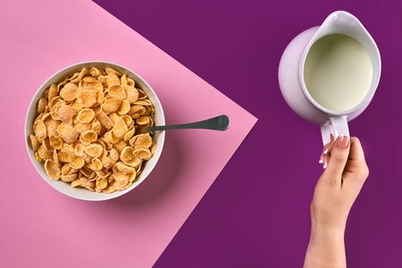 Food, healthy eating, people and diet concept - close up of woman eating muesli with milk for breakfast over purple and pink background. Copy space. Still life. Flat lay. Top viewの写真素材