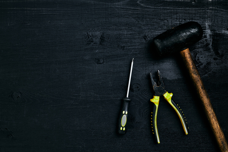 Screwdrivers, hammer, pliers and tools on a black wooden table. Top view. Copy space. Still life. Flat layの写真素材