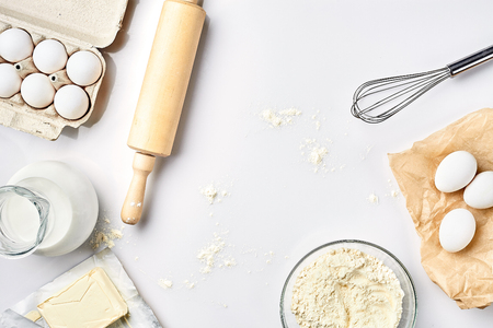 Preparation of the dough. A measurement of the amount of ingredients in the recipe. Ingredients for the dough: flour, eggs, rolling pin, whisk, milk, butter, cream. Top view, space for textの写真素材