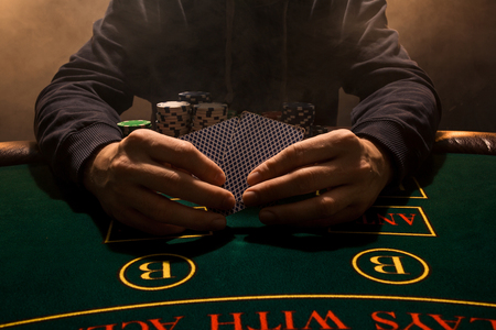 Mans hand with playing cards close up. Casino card game chips. Put on the table playing cards. Poker chips on the table.の写真素材