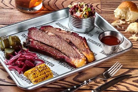 Smoked barbecue beef brisket with sauce, corn, marinated cucumber and onionsの写真素材