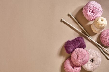 A group of colored balls of yarn and knitting needles on a beige background. Top view. Still life....