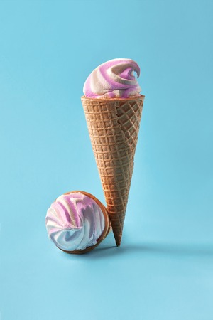 Ice cream in waffle cups, white and purple on light blue background.の写真素材