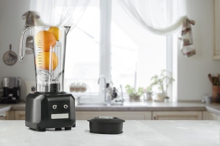 Blender and orange on wooden table in kitchenの写真素材