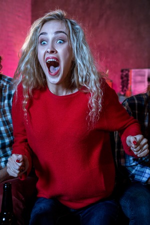 Emotional woman football fan at home sofa couch watching excitedの写真素材