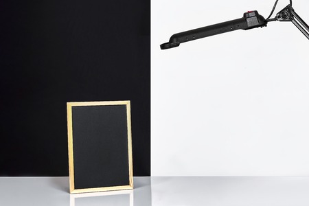 Blank blackboard on table near white and black wall.