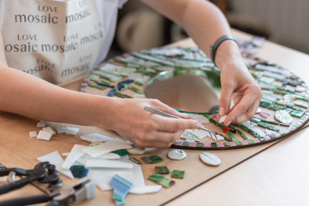 Workplace of the mosaic master: womens hands holding tool for mosaic details in the process of making a mosaicの写真素材
