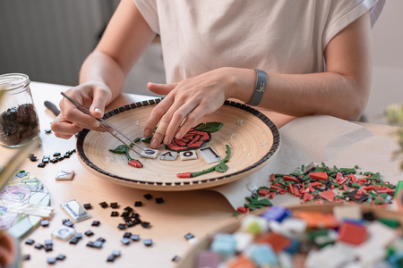 Workplace of a mosaic master: female hands laying out a mosaic element on the tableの写真素材
