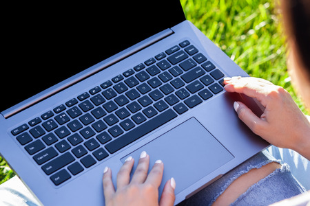 Close up hands on keyboard. Woman working on laptop pc computer with blank black empty screen to...