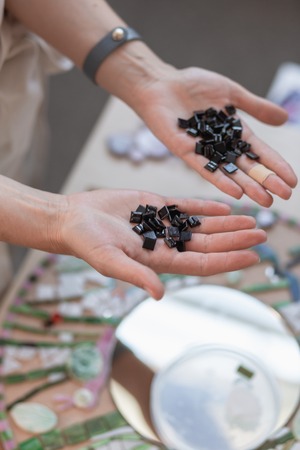 Workplace of the mosaic master: women's hands holding mosaic details in the process of making a mosaic. Close-upの写真素材