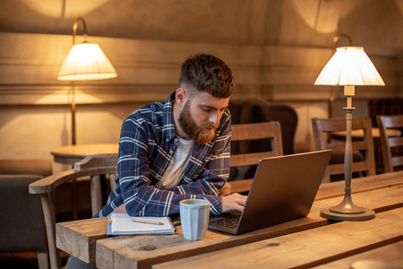 Young professional surfing the Internet on his laptop in a cafeの写真素材