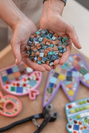Workplace of the mosaic master: womens hands holding mosaic details in the process of making a mosaicの写真素材