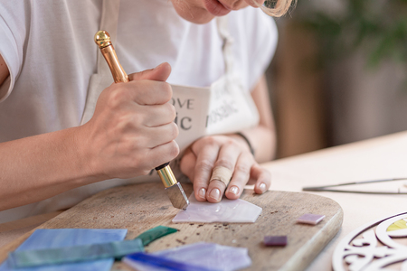 Artist cutting sheets of stained glass into small mosaic squares. Close-upの写真素材