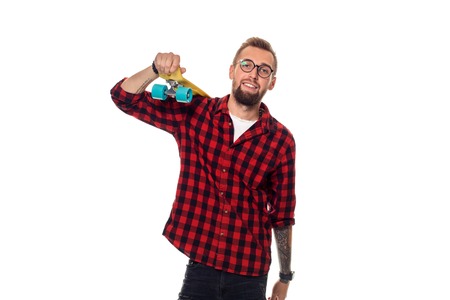 Hipster man over white background holding yellow skateboard. Active guy in plaid shirt with copy spaceの写真素材