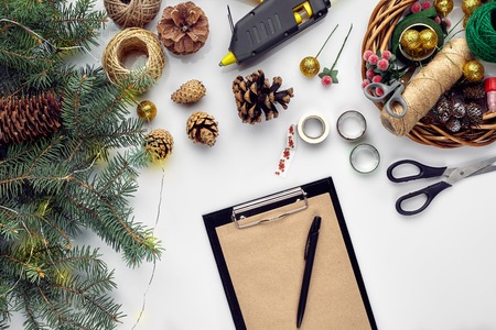 Preparing for Christmas or New Year holiday. Flat-lay of fur tree branches, wreaths, rope, scissors, craft paper over white table background, top view.の写真素材