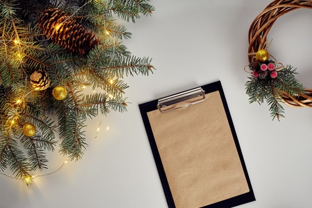 Flat lay of juniper wreath green pine tree branches, wreath and craft paper on white table, top view.の写真素材