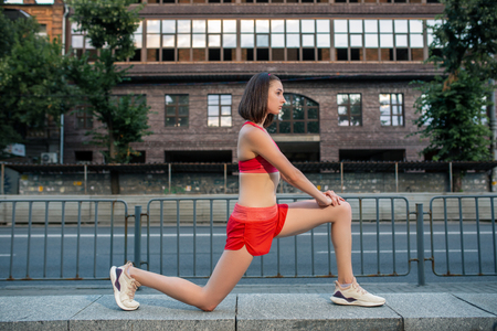 Sporty woman stretching and warming up legs before running urban fitness workout. Sport and healthy lifestyle concept.の写真素材