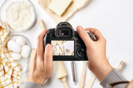 Digital single-lens reflex camera in hands. Man photographer makes photos. Male hands hold the camera close-upの写真素材