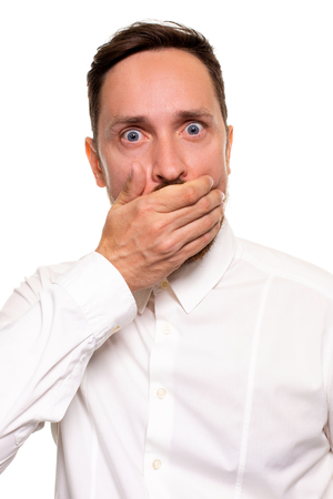 Portrait of amazed man covering his mouth over white background.の写真素材