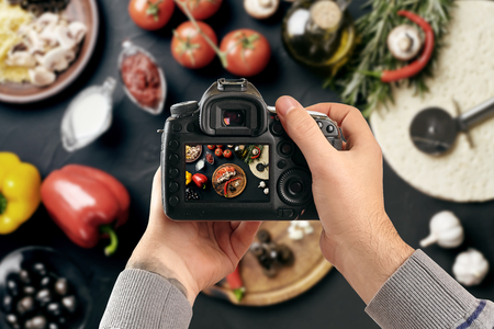 Digital single-lens reflex camera in hands. Man photographer makes photos. Male hands hold the camera close-upの写真素材