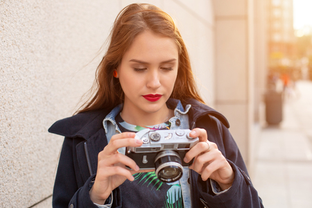 Outdoor autumn smiling lifestyle portrait of pretty young woman, having fun in the city with camera, travel photo of photographer.の写真素材