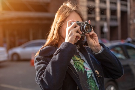 Portrait of a pretty young tourist taking photographs with vintage retro cameraの写真素材