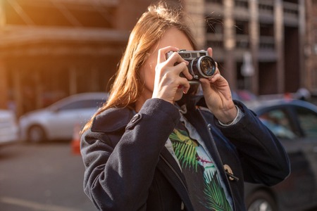 Portrait of a pretty young tourist taking photographs with vintage retro camera