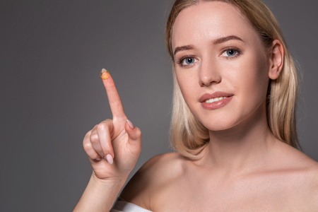 Young woman holding contact lens on index finger with copy space. Close up face of healthy beautiful woman about to wear contact lens.の写真素材