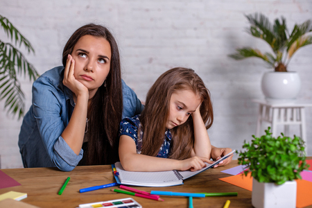 Mother becoming frustrated with daughter whilst doing homework sitting at the table at home in learning difficulties homework.の写真素材