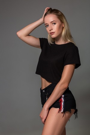 Beautiful blonde in a black t-shirt on grey background.