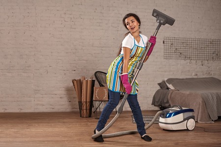 Happy woman cleaning home,dancing with vacuum cleaner and having fun, copy space.の写真素材