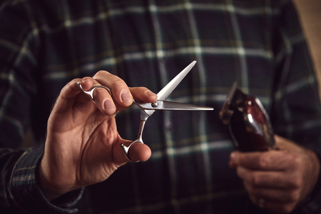 Barber is holding scissors and razor in his hands barbershop.