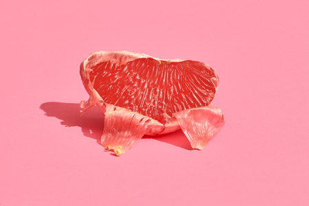 Half of grapefruit citrus fruit isolated on pinkの写真素材