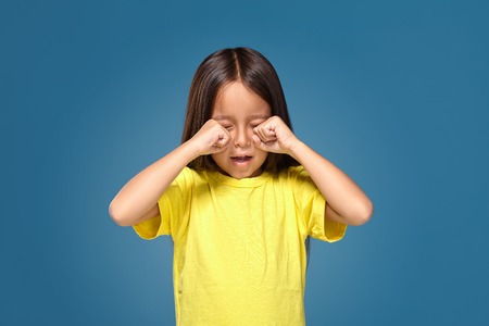 Sad offended little girl cries in yellow t-shirtの写真素材