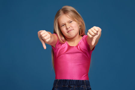 Portrait of emotional expressive little girl on blue backgroundの写真素材