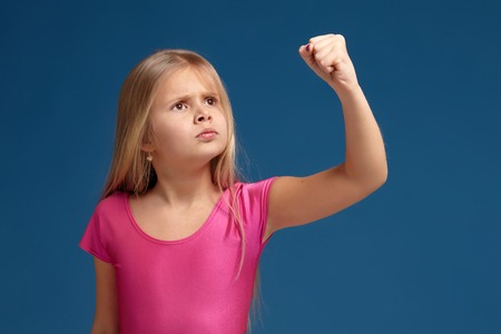 Portrait of emotional little girl on blue backgroundの写真素材