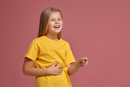 little girl in yellow t-shirt laughs pointing fingerの写真素材