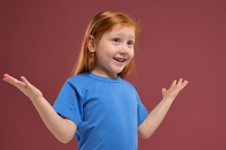 Portrait of cute redhead emotional little girl on red backgroundの写真素材