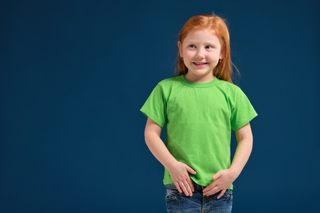 close up photo of little redhead emotional girl posing before camera on blue backgroundの写真素材