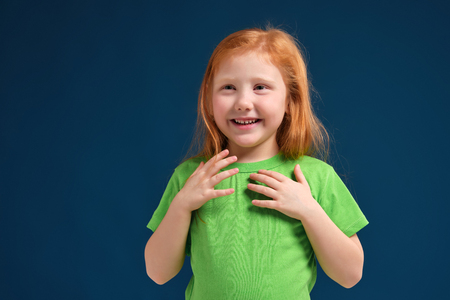 close up photo of little redhead emotional girl posing before camera on blue backgroundの写真素材