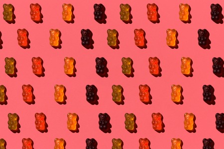 Pattern made of colorful jelly bears on coral background. Flat lay. Minimal conceptの写真素材