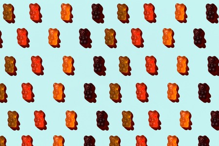 Pattern made of colorful jelly bears on aquamarine background. Flat lay. Minimal conceptの写真素材